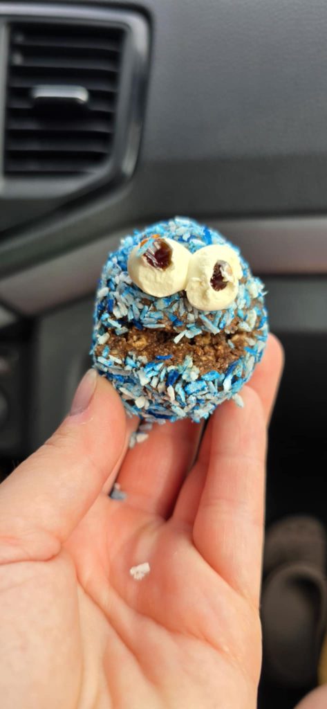 En väldigt glad chokladboll med blå koks, leende mun och två stora ögon.
